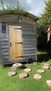 a wooden out house with a door and some rocks at Willowdene shepherds hut in Oswestry