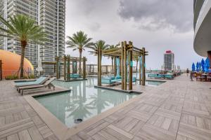een zwembad met stoelen, palmbomen en gebouwen bij Steps to Sand Ocean-View Condo in Hollywood in Hollywood