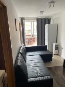 a living room with a leather couch and a window at Mac-Stephneil Holiday Homes in London