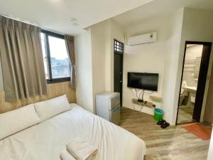 a bedroom with a white bed and a television at 台中 晴文旅 in Taichung