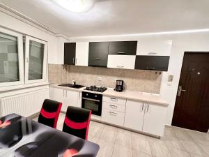 a kitchen with white cabinets and a table with red chairs at ADG 2 - Apartament cu 3 camere Timisoara in Timişoara