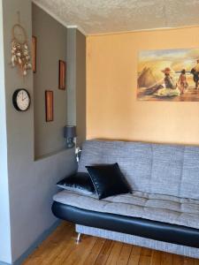 Studio tipa dzīvoklis في توكوموس: أريكة في غرفة معيشة مع ساعة على الحائط