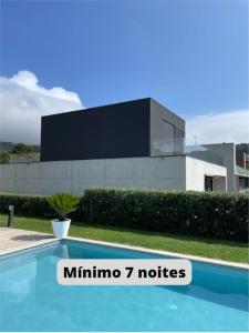 uma piscina com uma placa em frente a um edifício em Casas das Andoreiras em Moledo