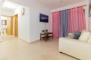 a living room with a white couch and a tv at Apartamento en ciudad Juan Bosh in Santo Domingo