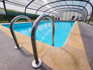a swimming pool with a canopy over it at Logis Hôtel Le Menobu in Theux