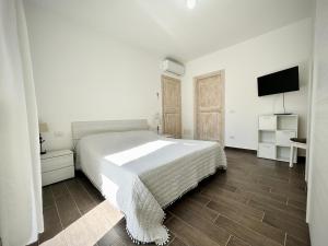 a white bedroom with a bed and a flat screen tv at Il Gioiello a Palau in Palau