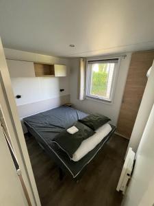 a small bed in a small room with a window at mobilhome JENNYFER et LOGAN in Onzain