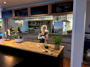 een vrouw die aan een bar in een restaurant zit bij Sotenäs Golfhotell in Hunnebostrand