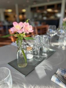 einen Tisch mit einer Vase mit rosa Blumen darin in der Unterkunft Sotenäs Golfhotell in Hunnebostrand