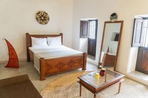 Schlafzimmer mit einem Bett, einem Spiegel und einem Tisch in der Unterkunft Tarawanda House by Stawi in Stone Town