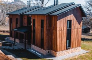 un pequeño edificio de madera con techo negro en El Refugio Ski & Summer Lodge en San Martín de los Andes