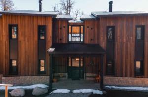 un gran edificio de madera con una puerta delantera con nieve en El Refugio Ski & Summer Lodge en San Martín de los Andes