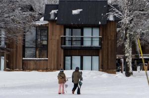 two people walking in the snow in front of a building at El Refugio Ski & Summer Lodge in San Martín de los Andes