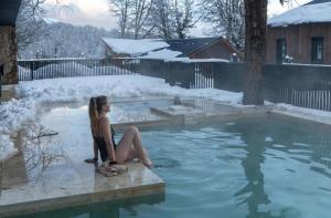 a woman sitting in a hot tub in the snow at El Refugio Ski & Summer Lodge in San Martín de los Andes +54 photos