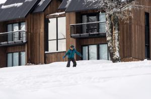 a person standing in the snow in front of a building at El Refugio Ski & Summer Lodge in San Martín de los Andes