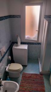 a bathroom with a toilet and a sink and a window at Romano Holiday 3 in Marina di Pescoluse +18 photos