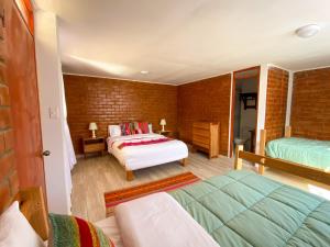 a bedroom with two beds and a brick wall at Tupac Huaraz in Huaraz