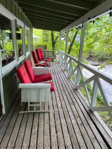 a porch with red chairs on a wooden deck at Rolling Brook Inn in Maggie Valley