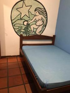 a bed with a painting of a mermaid on the wall at Mare Azzurro Praia do Itagua in Ubatuba