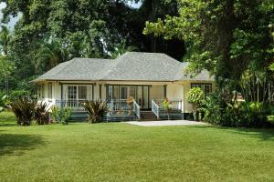 a small white house with a porch in a yard at Waimea Plantation Cottages, a Coast Resort in Waimea