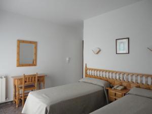 1 dormitorio con 2 camas, escritorio y espejo en Hotel Brisa en A Lanzada