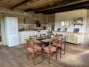 uma cozinha com mesa e cadeiras e uma geladeira branca em Maison charmante nature piscine chauffée em Montlauzun