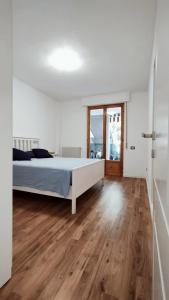 a white bedroom with a bed and a wooden floor at MareBlu Appartamento in Marina di Castagneto Carducci
