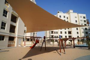 awning over a playground in front of a building at Azure Bliss - Cozy 1BR Haven in Baniyas, Near Baniyas Square in Abu Dhabi