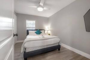 a white bedroom with a bed with a blue pillow at The Pearl Cottage 2b/1R with King and FAST WIFI in Tampa