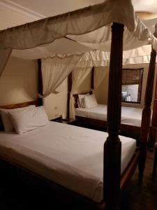 two beds in a bedroom with two canopy beds at Suite Elisir Domina Coral Bay in Sharm El Sheikh