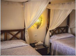 a bedroom with two beds with curtains and a lamp at Suite Elisir Domina Coral Bay in Sharm El Sheikh