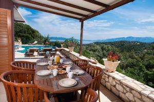 a dining table on a balcony with a view of the mountains at Andromeda by Vintage Travel in Meganisi