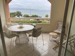 d'un balcon avec une table, des chaises et une grande fenêtre. dans l'établissement Superbe Pieds dans l eau ajaccio face à la mer plage de sable fin route des îles des sanguinaires, à Ajaccio