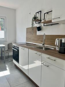 a white kitchen with a sink and a stove at Ferienwohnung Klein & Fein in Güstrow