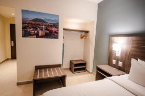 Habitación de hotel con cama y banco. en Hotel Centria en Monterrey