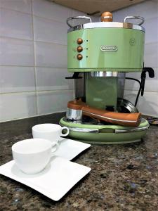 a green coffee maker with two cups on a counter at Prime Location! Detached Clifton Home with Parking in Bristol