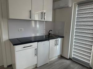 uma cozinha com um lavatório e armários brancos em Davud Apartments em Saraievo