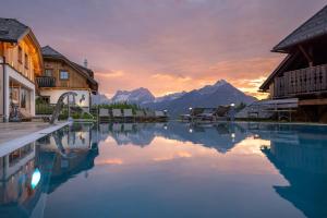 einen Pool mit Stühlen und Bergen im Hintergrund in der Unterkunft Almresort Baumschlagerberg in Vorderstoder