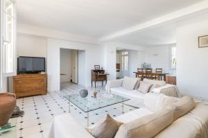 a living room with white furniture and a tv at Splendide vue sur ND de la Garde et le Vieux Port in Marseille