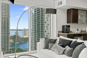 a living room with a white couch and a large window at Skyline Serenity - Brickell On The River - Bi-Level Loft with Breathtaking Views On The Ocean in Miami