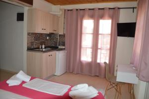 a bedroom with a bed and a kitchen with a window at Elite Suites in Afitos