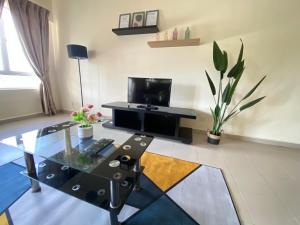sala de estar con mesa de cristal y TV en Tiara Desaru Private Beach NetFlix 3A13 By De Home, en Bandar Penawar