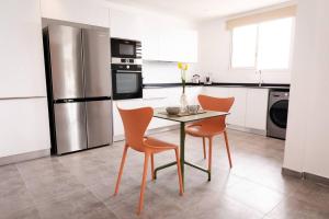 una cucina con tavolo, 2 sedie e frigorifero di TI PUNCH, appartement 3 pièces neuf, front de mer a Les Anses-d'Arlets