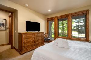a bedroom with a white bed and a flat screen tv at The Porches in Steamboat Springs