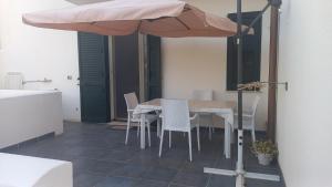 una mesa y sillas bajo una sombrilla en un patio en Nuovo appartamento vacanze, en Torre Pali
