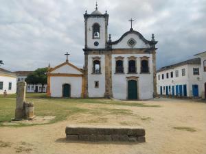 een oude kerk met een klokkentoren in een veld bij Pousada Rainha do Mar in Paraty