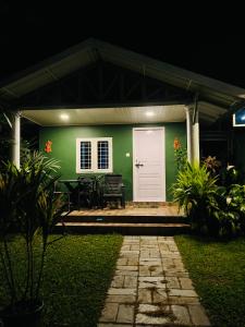 a green house with a white door at night at Fab Valley Homestay in Munnar