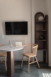 Kakóvolon的住宿－Fos Suites，一间带桌子和两把椅子以及电视的用餐室