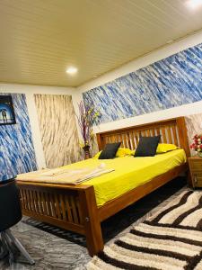 a bedroom with a bed with yellow sheets and a mural at Fab Valley Homestay in Munnar
