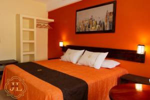 a hotel room with a bed with an orange wall at Hotel JL in Tierra Blanca